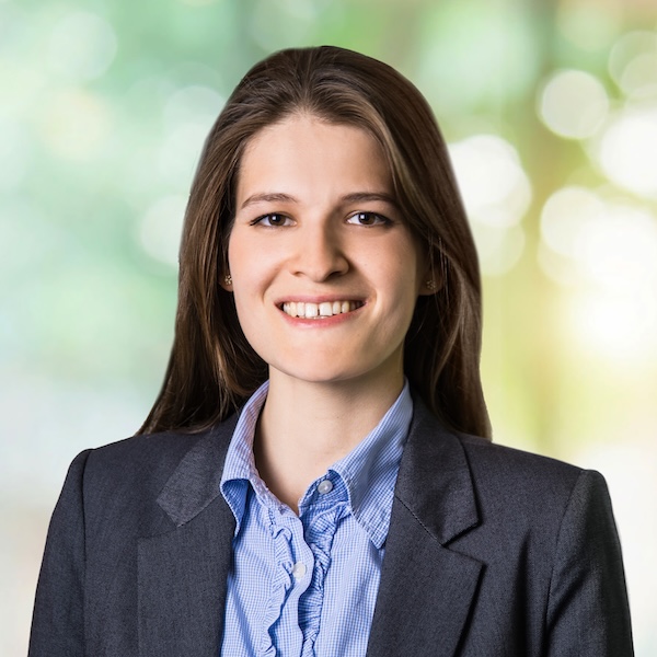 Porträt von Lorenza Caggiano mit langen, offenen Haaren und Blazer vor unscharfem Hintergrund mit Naturlicht