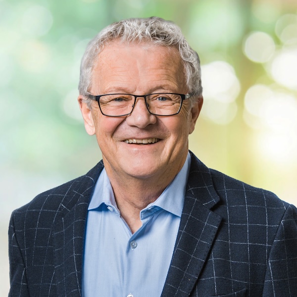 Porträt von Peter Dietrich mit Brille und kariertem Sakko vor unscharfem grünem Hintergrund