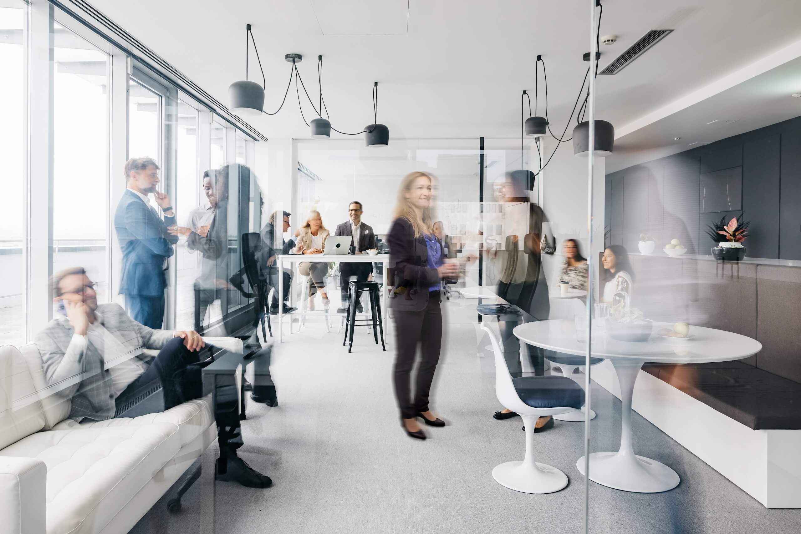 Moderne Business-Lounge mit Menschen in Bewegung und entspannter Gesprächsatmosphäre